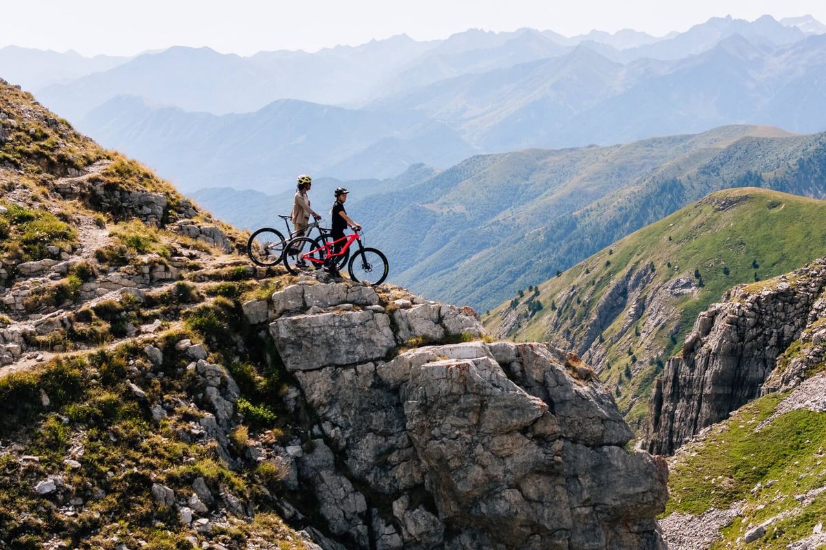 Ciclisti tenendo per mano la propria MTB guardano il paesaggio fermandosi lungo l'itineario del Colle Fauniera nelle terre del monviso, nella zona di cuneo in piemonte